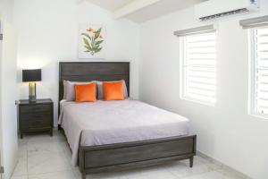 a bedroom with a bed with orange pillows at 101G Jolly Harbour, Garden View in Jolly Harbour