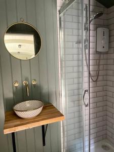 a bathroom with a sink and a mirror and a shower at Cosy Shepherds Hut Lyme Regis in Uplyme