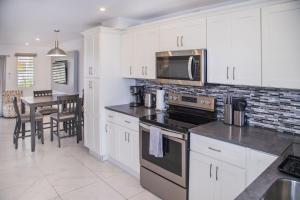 a kitchen with white cabinets and a table with chairs at 101H Jolly Harbour, Garden View in Jolly Harbour