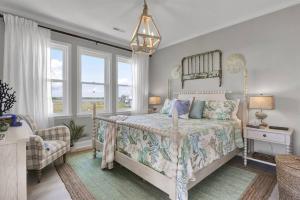 a bedroom with a bed and a chair and windows at Summer Coast House with hot tub and pool! in North Topsail Beach
