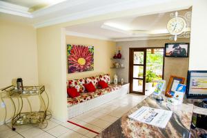 a living room with a couch with red pillows at Hotel Tubarão in Natal