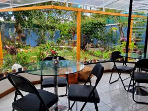 ein Restaurant mit einem Glastisch und Stühlen sowie einem Garten in der Unterkunft Casa Jardin del Mango in San José