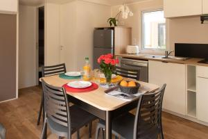 a kitchen with a wooden table with chairs and a dining room at Camping L'Oasis et California in Le Barcarès