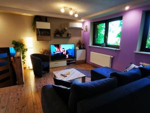 sala de estar con paredes de color púrpura y TV en Apartament Aldi en Bielsko-Biala