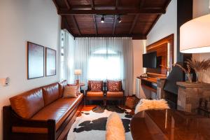 a living room with a leather couch and a table at Vila Suzana Parque Hotel in Canela