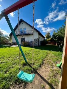 a swing in a yard with a house in the background at Wigierska Osada in Danowskie