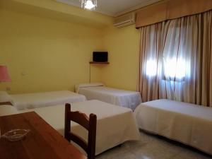 Habitación con 3 camas y mesa. en Hotel Restaurante Peñarroya en Argamasilla de Alba