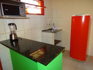 eine Küche mit einer Theke und einem roten Kühlschrank in der Unterkunft Apartamentos da Coló in Arembepe