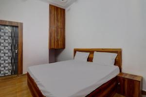 a bedroom with a bed with white sheets and a window at OYO Hotel Pitra Chaaya Hotel And Restaurant in Mathura