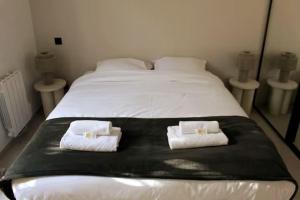 ein großes weißes Bett mit zwei weißen Handtüchern darauf in der Unterkunft Superbe Appartement avec Clim/Terrasse/Parking in Montpellier