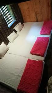 Cama grande con sábanas y almohadas rojas y blancas en Hoàng Công Bản Giốc Homestay en Cao Bằng