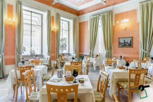 un ristorante con tavoli e sedie bianchi e finestre di HOTIDAY Hotel Verbania a Verbania