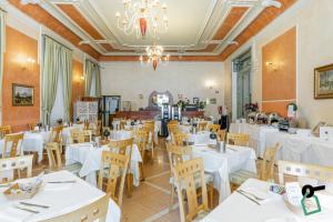 a restaurant with white tables and chairs and a chandelier at HOTIDAY Hotel Verbania in Verbania