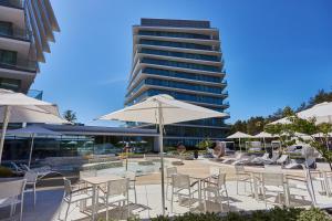 a group of tables and chairs with umbrellas and a building at Wave Family Apartment - Sea View in Międzyzdroje