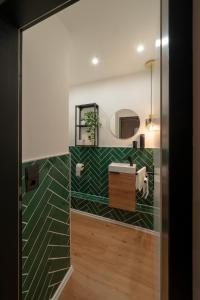 La salle de bains est pourvue de carrelage vert et blanc. dans l'établissement bevoflats - Stilvolles Souterrain am Mehringdamm, à Berlin