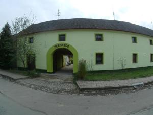 a large white building with an archway next to a street at Penzion Bernardo in Senička