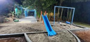 un parque infantil con un tobogán azul en la arena en Riverside Farm, en Murud