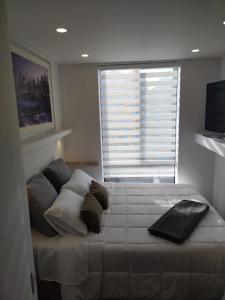a bedroom with a bed with pillows and a window at Soul Santa Bárbara executive, wifi 300 megas, Big Queen size bed, Smart tv Netflix, Walking distance to Unicentro Mall, Starbucks in front of the building, Top location in Bogotá