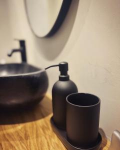a black soap dispenser next to a sink and a cup at Luxurious wooden detail flat in city center in Chalkida