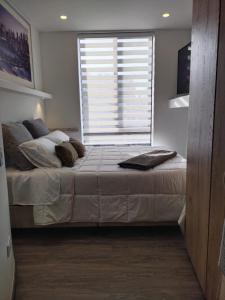 a bedroom with a large bed with a window at Soul Santa Bárbara executive, wifi 300 megas, Big Queen size bed, Smart tv Netflix, Walking distance to Unicentro Mall, Starbucks in front of the building, Top location in Bogotá