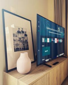 a television and a vase sitting on a wooden shelf at Luxurious wooden detail flat in city center in Chalkida