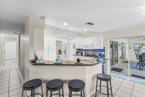 a kitchen with four stools at a counter with a counter top at Serene canal, three bedrooms and a large pool! - Villa La Brisa Fresca in Cape Coral