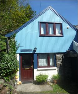 uma casa azul e branca com uma porta vermelha em Fisherman's Cottage em Tobermory
