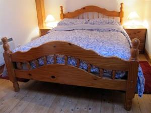 uma cama de madeira num quarto com duas mesas de cabeceira em Fisherman's Cottage em Tobermory