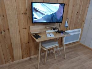 a wooden desk with a television on a wall at La Cabane 14 in Lanton