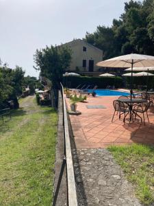 una valla con mesas y sombrillas junto a una piscina en Il Casalino, en Maratea