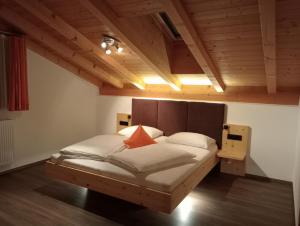 - une chambre dotée d'un grand lit avec des draps blancs et des oreillers orange dans l'établissement Ferienwohnungen Zeppenhof, à Santa Valburga