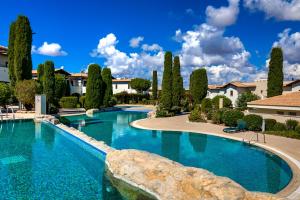 a large swimming pool with trees and houses at 2 bedroom Apartment Assia with communal pool, Aphrodite Hills Resort in Kouklia