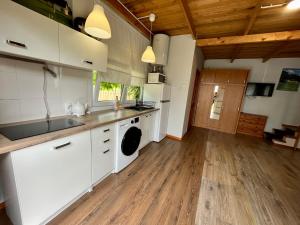 a kitchen with white cabinets and a wooden floor at Wigierska Osada 2 in Danowskie