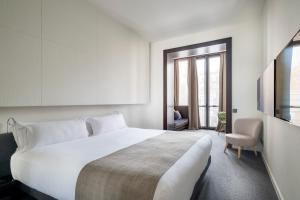a bedroom with a large white bed and a chair at Sixtytwo Hotel in Barcelona