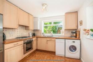 cocina con armarios de madera y lavavajillas blanco en Beautiful cottage near London, en Maidenhead