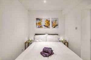 a bedroom with a white bed with two paintings on the wall at Luxury Oasis in London