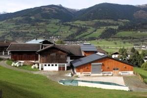 un groupe de bâtiments sur une colline avec des montagnes en arrière-plan dans l'établissement Stöcklgut Apartment, 