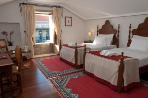 - une chambre avec 2 lits, une table et un bureau dans l'établissement Casa Melo Alvim - by Unlock Hotels, à Viana do Castelo