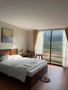 um quarto com uma cama e uma grande janela em Aurora's House em Dong Van