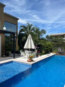 佛羅安那波里的住宿－Suite em linda casa em Jurerê internacional，一个带桌椅和遮阳伞的游泳池