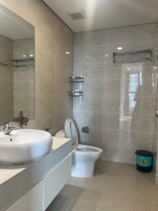 La salle de bains est pourvue d'un lavabo blanc et de toilettes. dans l'établissement VINHOMES GARDENIA, à Hanoï