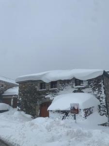 una casa con nieve encima en Habitaciones Frade, en O Cebrero