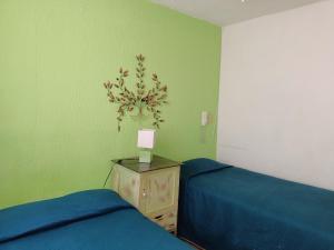1 dormitorio con 2 camas y mesita de noche con lámpara en Casona Luciérnaga-Casa de Huéspedes en León