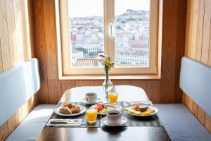 a table with two plates of food and a window at Lisboa Pessoa Hotel in Lisbon