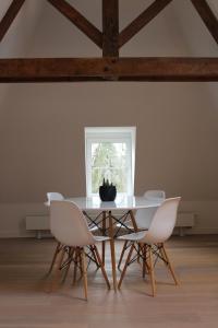 mesa de comedor con sillas blancas y ventana en Un Toit sur les Monts en Esneux