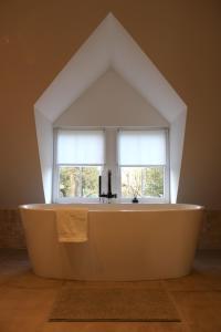 una grande vasca da bagno bianca di fronte a una finestra di Un Toit sur les Monts a Esneux