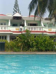 un hôtel avec une piscine en face d'un bâtiment dans l'établissement Mint Villa, Benaulim, Goa, à Benaulim