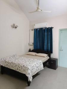 - une chambre avec un lit et un rideau bleu dans l'établissement Mint Villa, Benaulim, Goa, à Benaulim