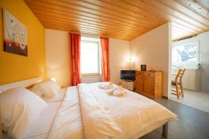 1 dormitorio con 1 cama blanca grande y techo de madera en Haus Padrun, Apartment nr.3, en Arosa