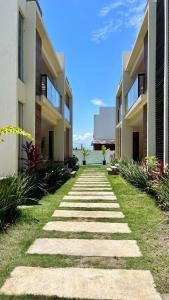 a walkway between two buildings with grass at Ap em barra grande c/ piscina in Marau